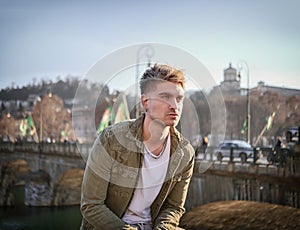 Man sitting on ledge in front of bridge