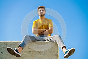 Man sitting on a ledge looking around