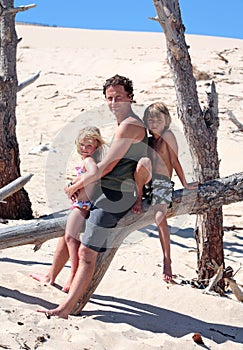 Man sitting on a log with his son and daughter