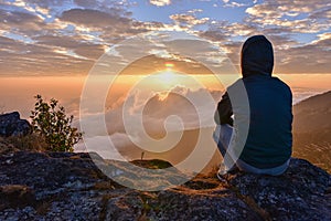 Man sitting on a mountain for watching Sunrise views.