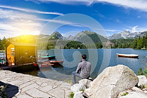 Man sitting near alpine mountain lake