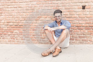 Man sitting near brick wall and smiles