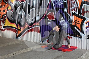 Man sitting near graffiti wall