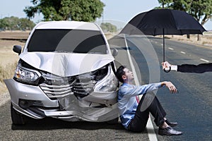 Man sitting next to dented car photo