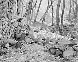 Man sitting next to a fire in the woods and reading a book