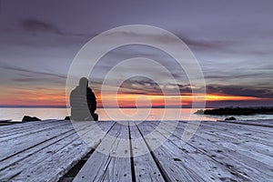 Man sitting on the pier and watching the sunset