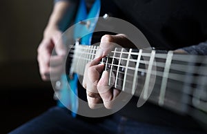 a man sitting and practicing electric guitar on dark background