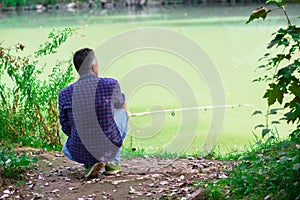 Man sitting on the river bank and fishing, summer outdoor. Sesonal leisure. Fishing.