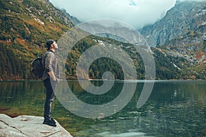 man sitting on the rock in front of lake in mountains enjoying the view