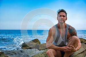 Photo of a man enjoying the peacefulness and serenity of the ocean while sitting on a rock photo