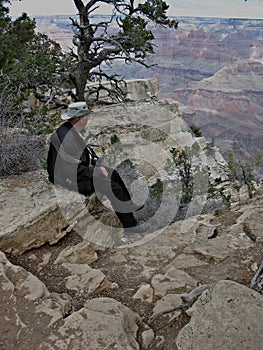 Man sitting on a Rock Overlooking the Grand Canyon