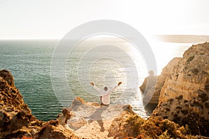 Man sitting on the rocks with open arms to the ocean view