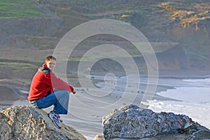 Man Sitting on Rocky Beach