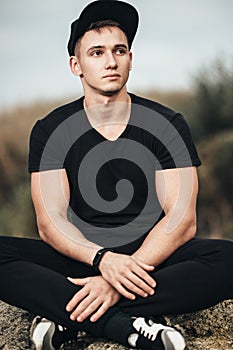 Man sitting on rocky beach in the sunset at the sea.