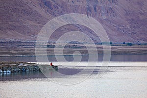 A man is sitting on the shore of the Dead Sea A man sitting yoga in tropical island with blus sky and blues gradient