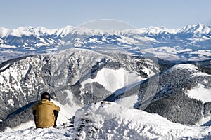 Man sitting on snow and looking on the winter hills