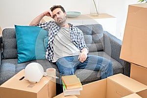 Man sitting on sofa with belongings in living room ready to move