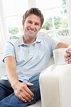 Man Sitting On Sofa Drinking Coffee Relaxing At Ho