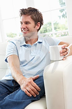 Man Sitting On Sofa Drinking Coffee Relaxing At Ho