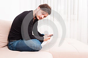 Man sitting on sofa holding smartphone and texting