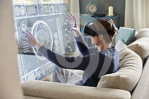 Man Sitting On Sofa At Home Wearing Virtual Reality Headset