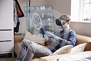 Man Sitting On Sofa At Home Wearing Virtual Reality Headset