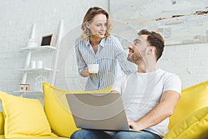 Man sitting in sofa with laptop and talking to girlfriend