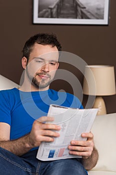 Man sitting on sofa relaxed and reading magazine.