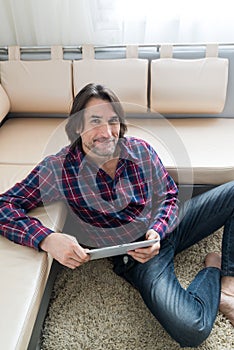 Man sitting in sofa using electronic tablet