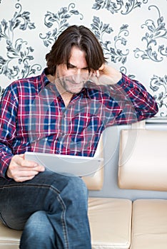 Man sitting in sofa using electronic tablet