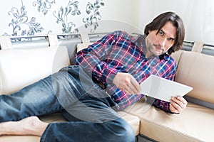 Man sitting in sofa using electronic tablet