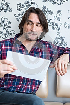 Man sitting in sofa using electronic tablet