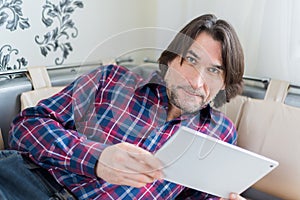 Man sitting in sofa using electronic tablet