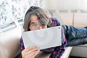 Man sitting in sofa using electronic tablet