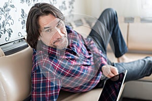 Man sitting in sofa using electronic tablet