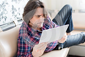 Man sitting in sofa using electronic tablet