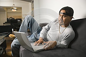 Man sitting on sofa using laptop.
