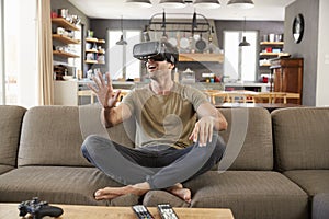 Man Sitting On Sofa Wearing Virtual Reality Headset