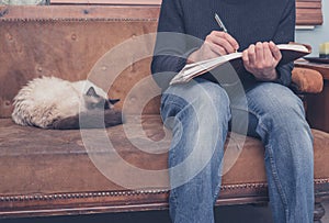 Man sitting on sofa writing ion notebook