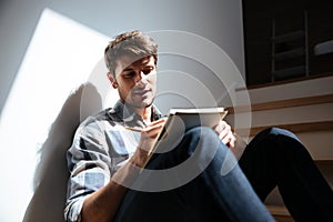 Man sitting on stairs at home and writing in notepad