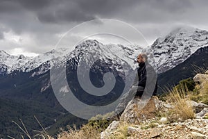 A man sitting on a stone in the mountains in winter