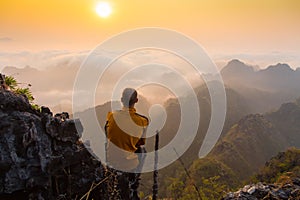 Man sitting on stone top of high mountain