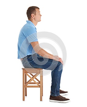 Man sitting on stool against white background