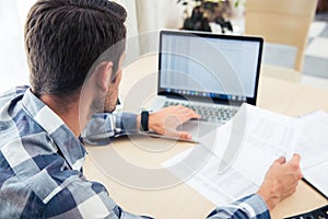 Man sitting at the table with bills and laptop