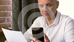 Man Sitting at Table Looking at Cell Phone