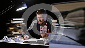 Man sitting at the table nervously crumples sheets. Black background