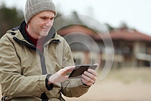 Man sitting with tablet on the winter beach