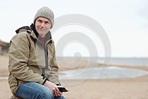 Man sitting with tablet on the winter beach