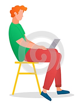 Man sitting on the tabouret and working with laptop in social networks holding computer on his knees