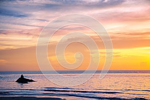 Man sitting and thinking on the rock at sunset